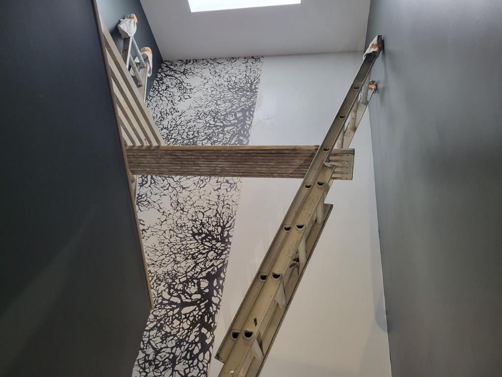 Overhead view of stairwell with black tree-branch wallpaper being installed